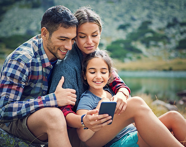 Man, woman, and girl looking at smartphone